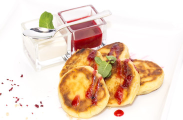 cheesecakes with sour cream and jam on table in restaurant