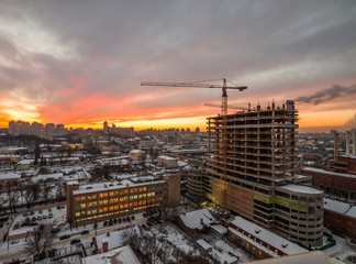 Crane in the construction site under the sunset and winter city