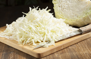 Chopped cabbage strips on a cutting board and a head of cabbage.