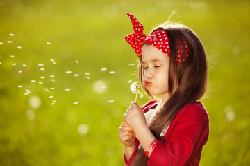 Beautiful little girl blowing dandelion