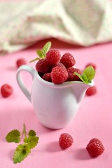 Ripe raspberries on pink background and fabric