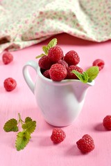 Ripe raspberries in a white jug with fabric