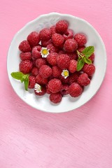 Ripe raspberries in a white plate with mint