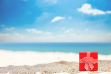 Gift box with ribbon on the sand