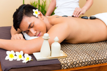 Obraz na płótnie Canvas Indonesian man at hot stone wellness massage