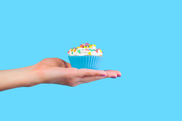 Hand holding cupcake on blue background