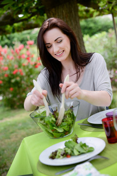 cheerful cute young woman eat salad at barbecue party 