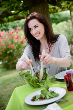 cheerful cute young woman eat salad at barbecue party 