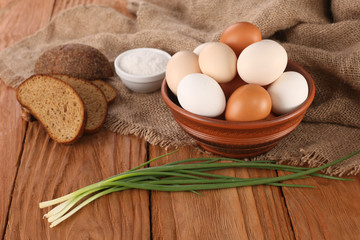 Fototapeta na wymiar raw eggs in an earthenware bowl, onions, bread, salt shaker