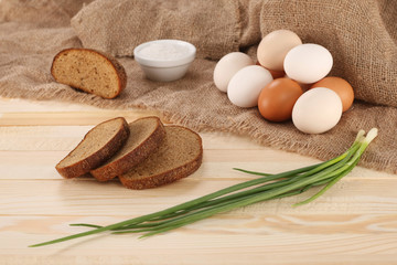 Fototapeta na wymiar raw eggs in an earthenware bowl, onions, bread, salt shaker