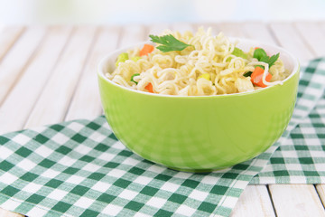 Tasty instant noodles with vegetables in bowl on table close-up