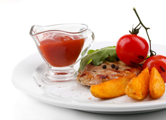 Grilled steak with fried potato pieces and grilled vegetables,