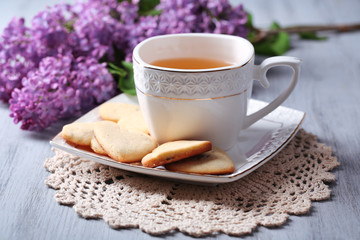 Lavender cookies and cup of tasty tea on color wooden