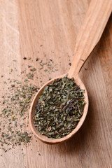 Spice greens in spoon on wooden background