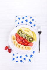 Various sliced fruits on plate on table close-up