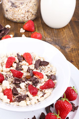 Healthy cereal in bowl with strawberries and chocolate