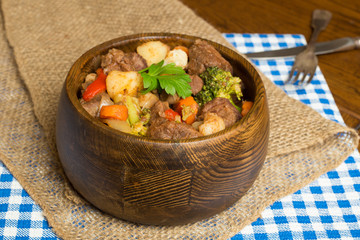 Hearty beef stew in wooden bowl