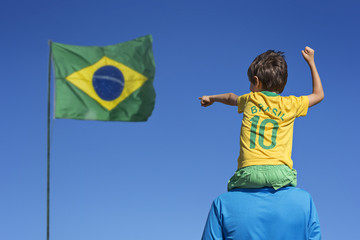 Garçon et son père regardant le drapeau brésilien