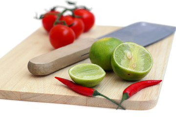 chillis, lime and tomato on a chopping board and the knife isola