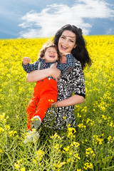 Laughing mother and son in canola field