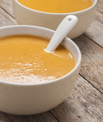 two bowls of squash soup on wooden table close up