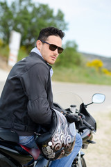 handsome young biker man riding a black motorbike 