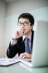 Fototapeta premium Young handsome man using laptop in his office