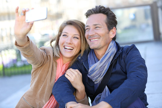 Mature couple taking picture with smartphone