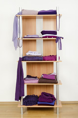 Tidy wardrobe with purple clothes nicely arranged on a shelf.