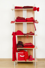 Obraz na płótnie Canvas Schludne ubrania z czerwonego ubrania ładnie ułożone na półce.