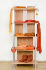 Obraz na płótnie Canvas Schludne ubrania z pomarańczowymi ubrania ładnie ułożone na półce.