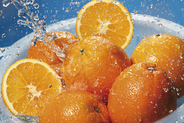 Fototapeta na wymiar Spritzwasser auf frische Orangen im Sieb