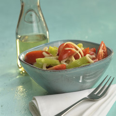 Griechischer Salat mit Tomaten und grüne Paprika,eine Flasche Olivenöl im Hintergrund