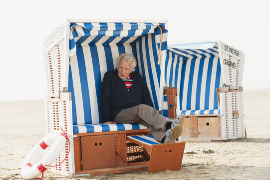 Deutschland,St. Peter-Ording,Nordsee,älterer Mann entspannt auf Strandkorb - Powered by Adobe