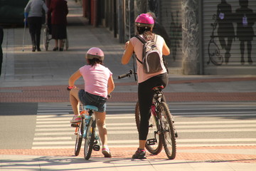 Madre e hija yendo en bicicleta en la ciudad - obrazy, fototapety, plakaty