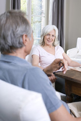 Obraz premium Senior Paar sitzt im Wohnzimmer,lächelnd,Porträt