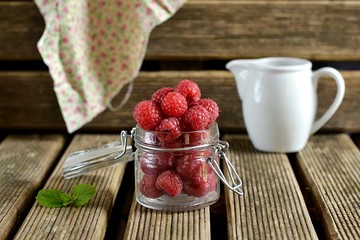 Raspberries in a jar on wooden background