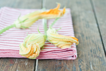 Italien,Toskana,Magliano,Nahaufnahme von Zucchini Blume mit Serviette auf Holztisch