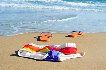 rainbow swimsuit and flip-flops in the sand of a beach