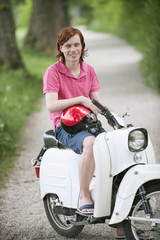 Fototapeta na wymiar Deutschland,Bayern,Junger Mann auf Moped,lächelnd,Porträt