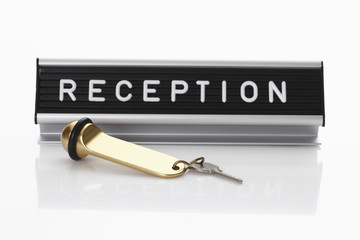 Empfangsschild mit Hotelschlüssel auf weißem Hintergrund