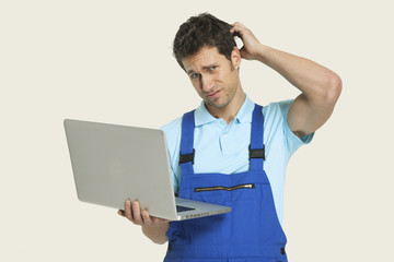 Mann im Gesamt hält Laptop und Kratzen Kopf,Portrait