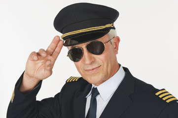  Flugkapitän salutiert vor weißen Hintergrund,lächelnd
