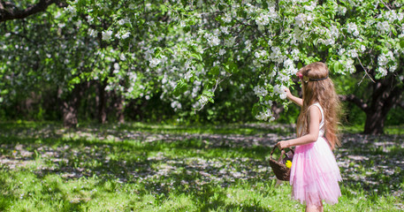 Fototapeta na wymiar Cute little girl in blossoming apple orchard at sunny day