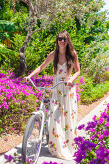 Young woman on vacation biking at flowering garden