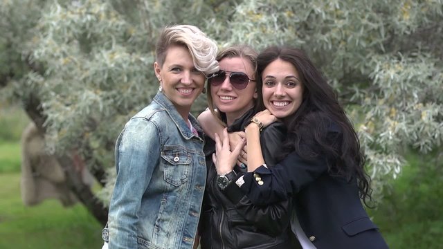 Three beautiful women girlfriends posing on camera