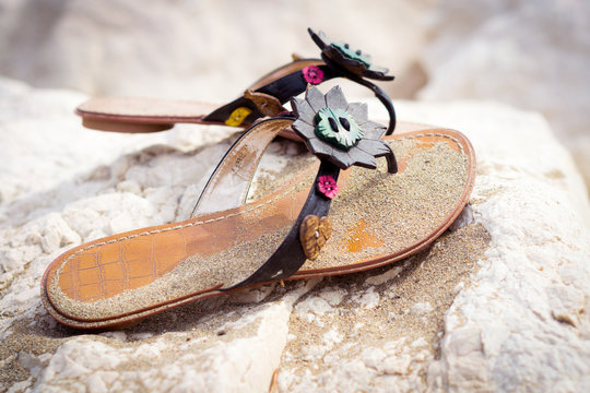 Summer sandals on a sandy beach standing on a rock
