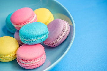 colorful macaroons in plate on blue background