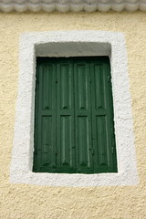 green painted wood Mediterranean Shutters set in pink wall	