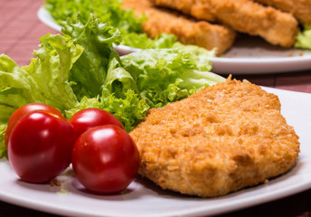 Fried battered chicken breast fillet  with lettuce on the plate